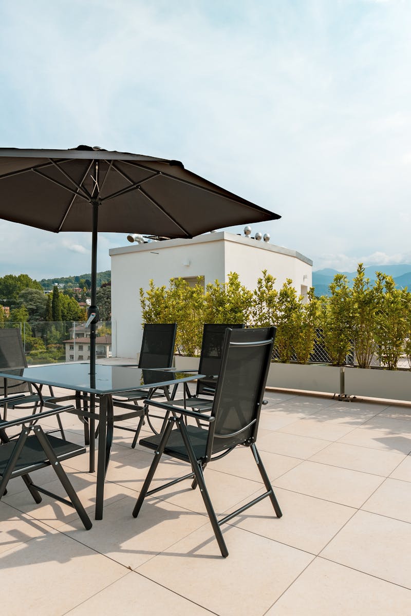 Sunny terrace with furniture, umbrella, and mountain views. Ideal for outdoor relaxation.