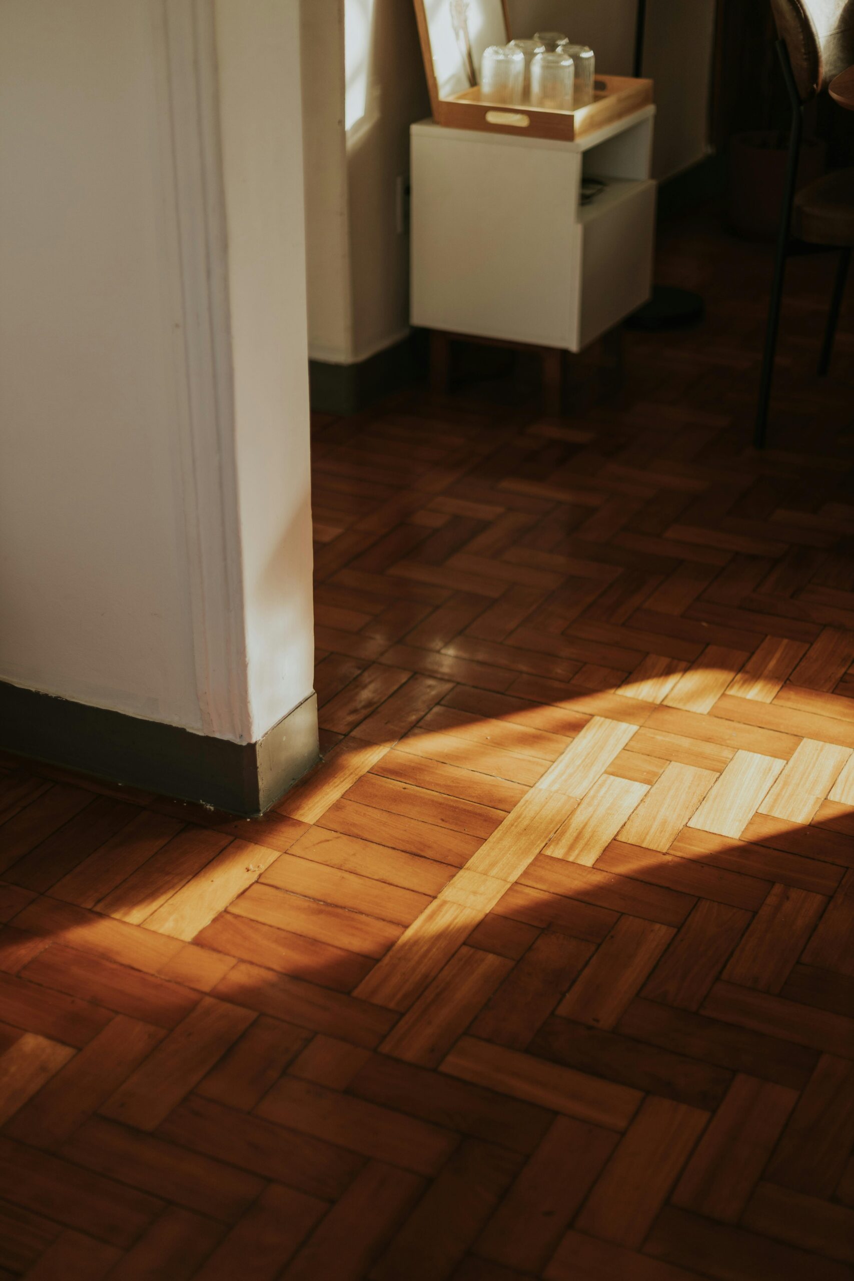 Warm sunlight cast on wooden parquet flooring in a cozy indoor setting.
